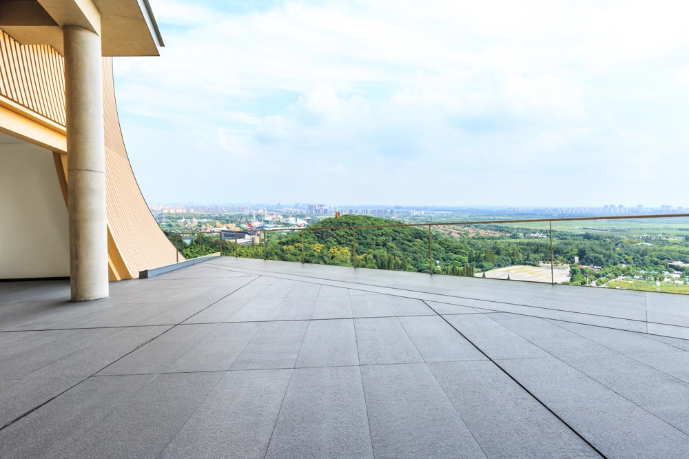 Tarasy z płyt betonowych: nowoczesna przestrzeń z przeszkloną balustradą i widokiem na zalesiony teren